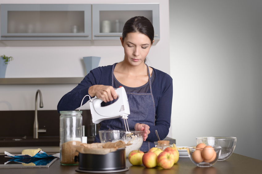 Junge Frau nutzt einen Handmixer